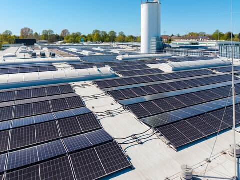 Large rooftop solar power installation on an industrial building under clear blue sky.