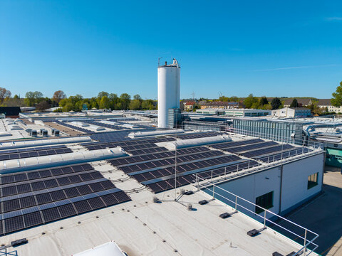 Large rooftop solar power installation on an industrial building under clear blue sky.