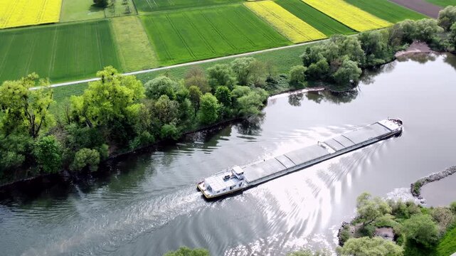 Drohne fliegt &uuml;ber Fluss mit Binnenschiff, Ufer mit Auwald und Agrarland, Luftaufnahme