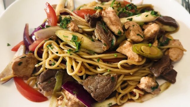 Close-up of Peruvian dish Tallarines Saltados served on a plate. Stir-fried noodles with beef and vegetables, traditional Peruvian chifa cuisine. High quality 4k footage