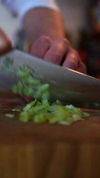 Close up of chef chopping fresh green celery stalks on a wooden cutting board