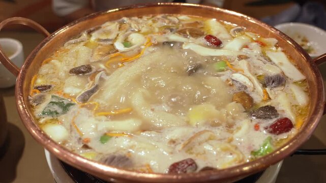 Chinese hot pot bubbling with mushrooms and herbal soup