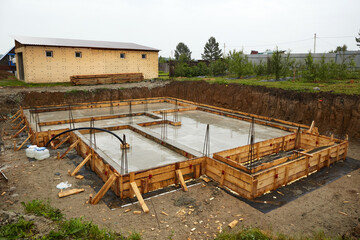 Fototapeta premium A concrete foundation is being poured on the construction site. Wooden formwork is used.