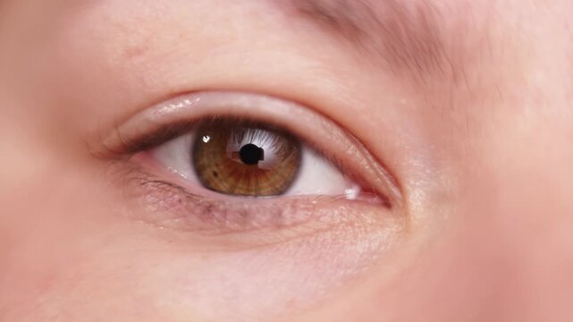 Extreme close-up of a human eye with brown iris and detailed skin texture