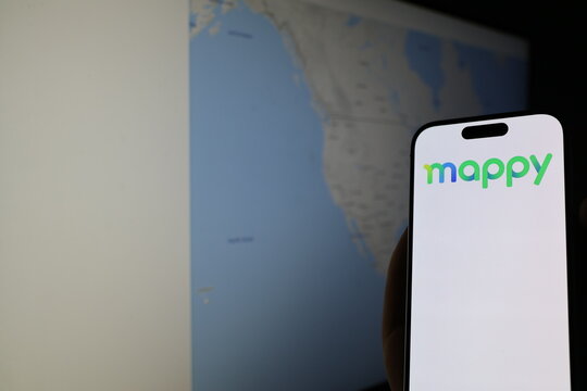 Kiel, Germany - 05-20-2026: Smartphone displaying French mapping software company Mappy logo in front of companys webpage