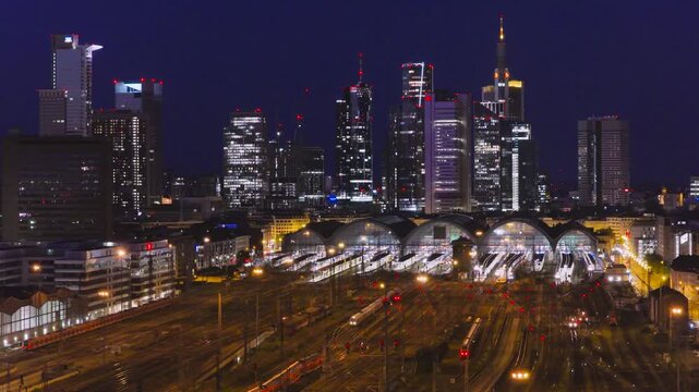 Aerial view of the illuminated Hauptbahnhof train station and the modern skyscraper skyline at night in Frankfurt am Main, Hessen, Germany.