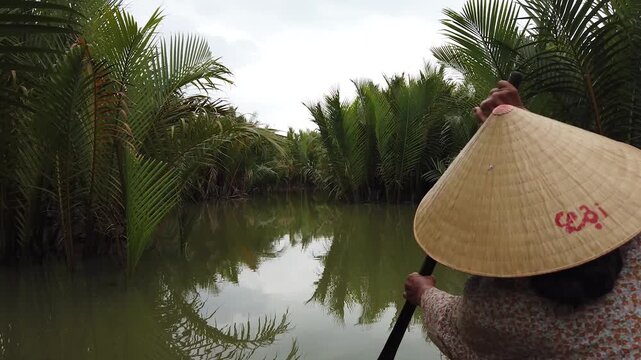 Person paddling boat in coconut palm canal near Hoi An Vietnam