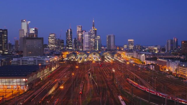 Aerial view of Hauptbahnhof central station with illuminated tracks and the city skyline at twilight in Frankfurt am Main, Hessen, Germany.