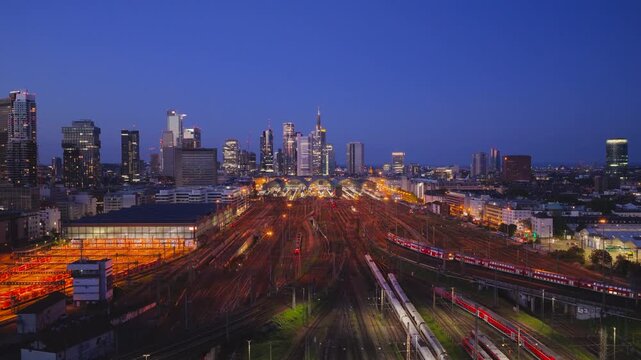 Aerial view of Hauptbahnhof with illuminated train tracks and the modern city skyline at dusk Frankfurt am Main, Hessen, Germany.