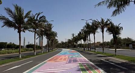Bright street art on Jeddah waterfront walkway with palm trees and modern skyscrapers in jeddah saudi arabia © mohamed alhamami