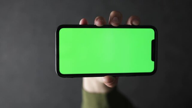 Hand holding smartphone with green screen for easy keying and customization