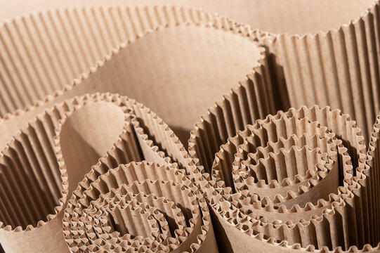 Rolled corrugated cardboard packaging in close up. Brown kraft paper texture with layered folds and ribbed surfaces. Sustainable shipping background for industrial design and