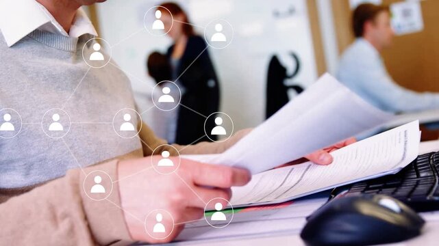 Desk worker sifting papers for business, causing network nodes overlaying hands, pointing to page