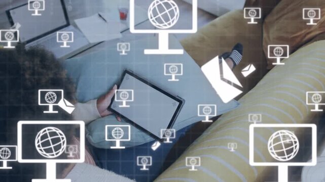 Woman holding tablet on sofa, tablet generating icons and binary expanding, visualizing tech data