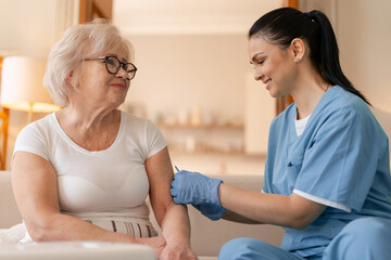 Nurse vaccinating senior woman at home