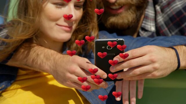 Couple sitting bench, tapping phone, activating AR hearts floating around hands, using dating app
