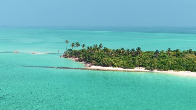 Aerial view of a tropical island with white sand beaches and lush palm trees surrounded by turquoise ocean water in Hoarafushi, Haa Alif, Maldives.