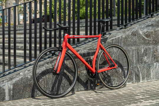 Red fixed gear bicycle parked near urban stairs outdoors