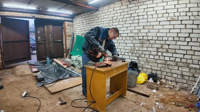 Skillful handyman wearing protective gear grinding a metal part in his workshop, with bright sparks flying from the spinning abrasive disc during the industrial metalworking process
