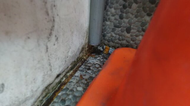 Water drips from the pipe and flows onto the ceramic floor with a pebble texture