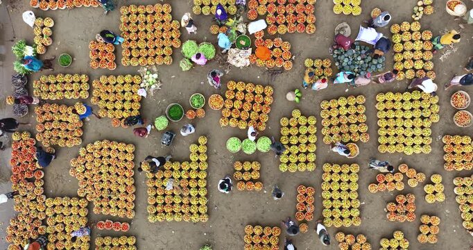 Aerial view of vendors and customers at a busy outdoor market with baskets of fresh produce arranged in grids on the ground in Sylhet, Sylhet Division, Bangladesh.