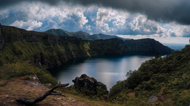 Majestic mountain lake volcanic crater with dramatic cloud over green cliff and lush forest scenic landscape tranquil water island nature