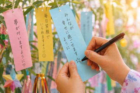 七夕短冊に願いを書く手元と笹飾りがぼける幻想的な日本の夏風景