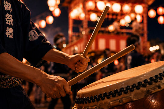 提灯が灯る盆踊り会場で太鼓を打つ手元と熱気あふれる日本の夏祭り風景