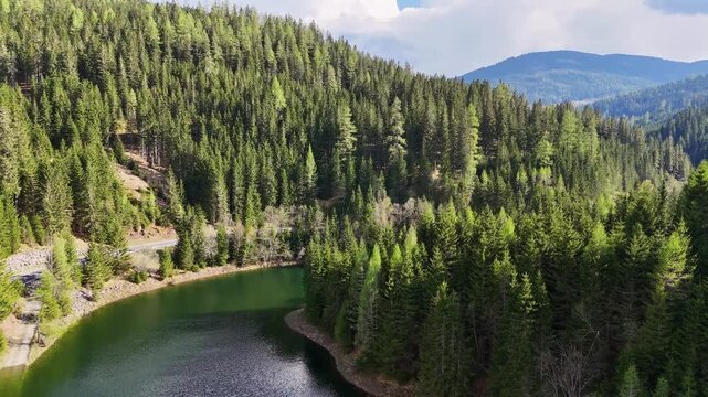 Aerial view of the Kraftwerk Bodendorf and Sperre Paal reservoir surrounded by dense evergreen forests and rolling hills in Murau, Styria, Austria.