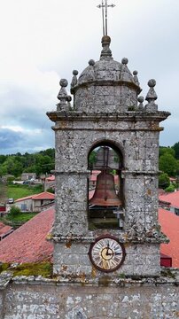 Aerial view of the historic stone bell tower and clock of Iglesia de Santa Marina in Augas Santas, Ourense, Spain.