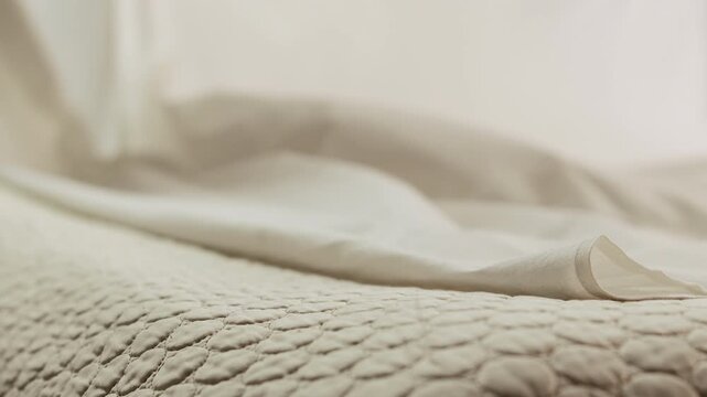 At home man in white shirt throws a sheet onto the double bed with his hands