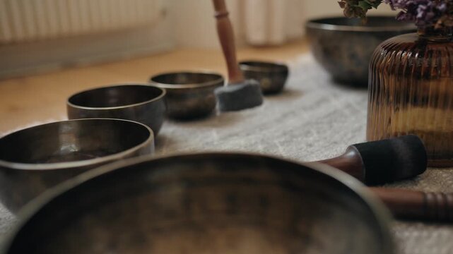 A mallet strikes a row of Tibetan singing bowls one by one from far to near