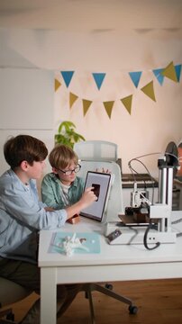 Kids examine and test a 3D printed part in their hands, near working 3D printer