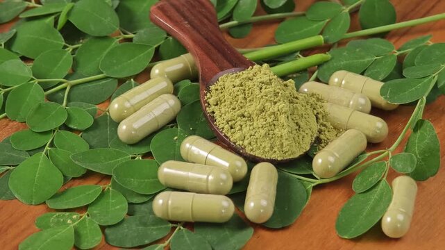 moringa leaf and powder capsule on wooden background