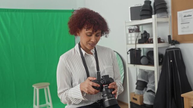 Woman holding dslr camera with hands, adjusting lens while seated in studio; confidence creative professionalism.