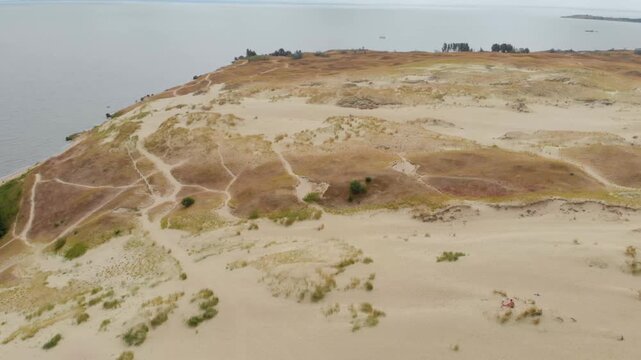 An aerial drone shot captures the vast, wind swept sand dunes of the Curonian Spit, a UNESCO World Heritage site in Neringa, Lithuania.