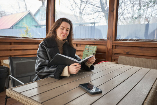 Woman reading a book on a wooden table in a cozy outdoor shelter