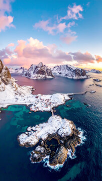 Luftbild der verschneiten Lofoten mit Bergen und Meer bei Sonnenuntergang