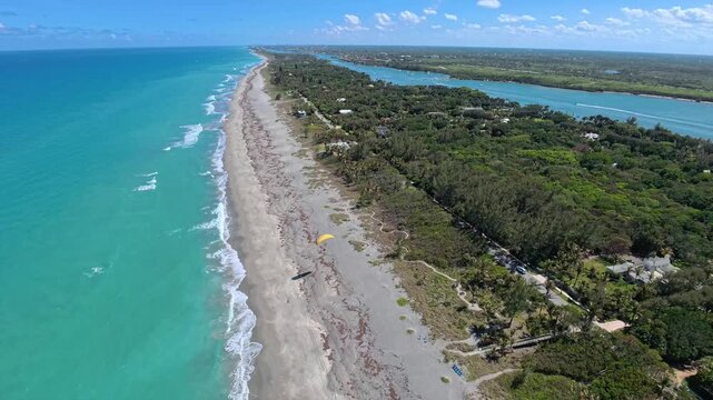 Aerial view of the sandy beach and turquoise ocean waters along the lush coastline of Jupiter Island, Florida, United States.