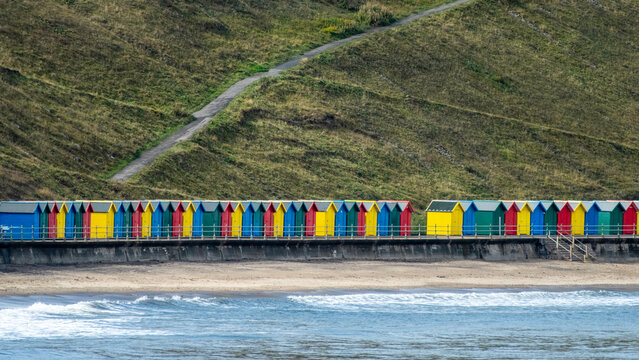 Colourful beach cabins in front of cliff