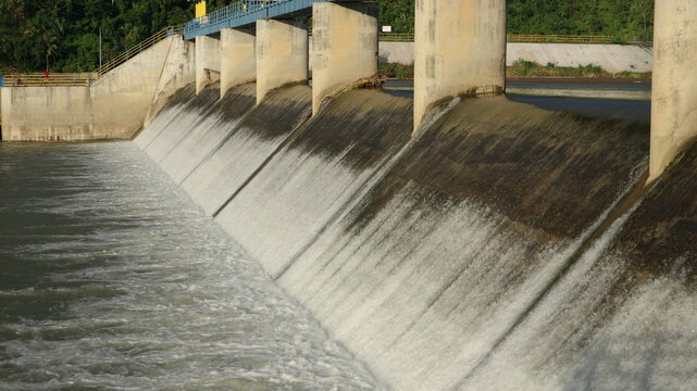 Water rushes over a concrete dam under cloudy skies