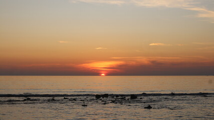 Fototapeta premium Sun dips low, painting sky in soft orange and pink hues