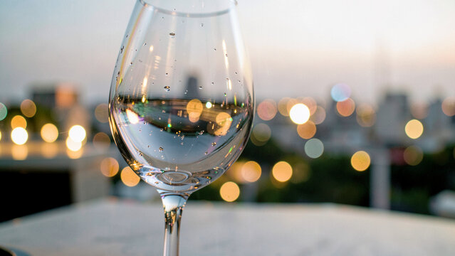 Glass stemware capturing warm golden urban bokeh lights at twilight