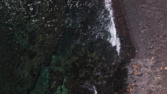 Top Down Aerial of Volcanic Black Rock Coast and Turquoise Water at Playa del Jablito Fuerteventura