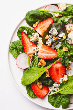 Summer salad with strawberries, lettuce leaves, dorblu cheese, and walnuts. Summer dishes and salads 