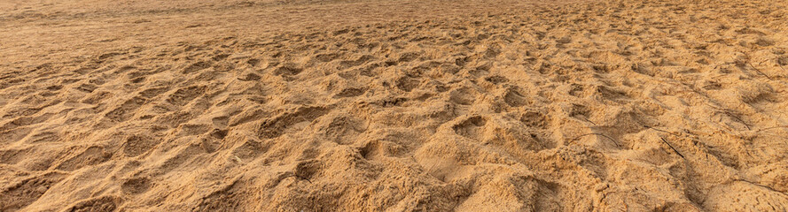 High angle view of textured golden sand background,A high angle panoramic shot of fine golden sand texture with footprints and uneven surfaces, perfect for a natural background or abstract summer. © banjongseal324