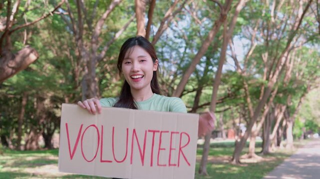 Volunteer Advocate: A young woman, holding a sign that proudly declares VOLUNTEER, stands amidst a verdant landscape, radiating a warmth of selfless dedication.