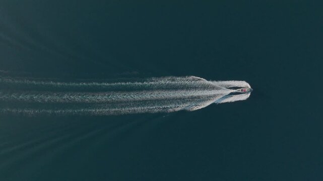 Aerial view of a motorboat cruising through deep blue water and creating a long white wake Syracuse, Sicily, Italy.