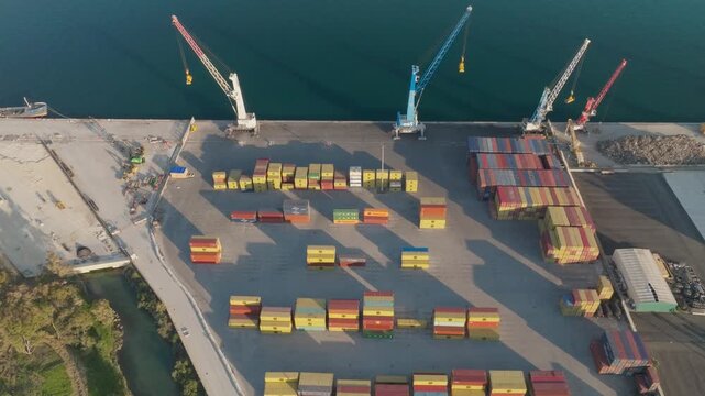 Aerial view of the industrial container port in Augusta with tall cranes and colorful shipping containers on the pier in Syracuse, Sicily, Italy.
