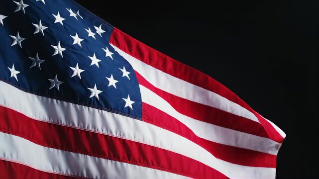 A close-up shot of the stars and stripes of a waving flag against a dark background